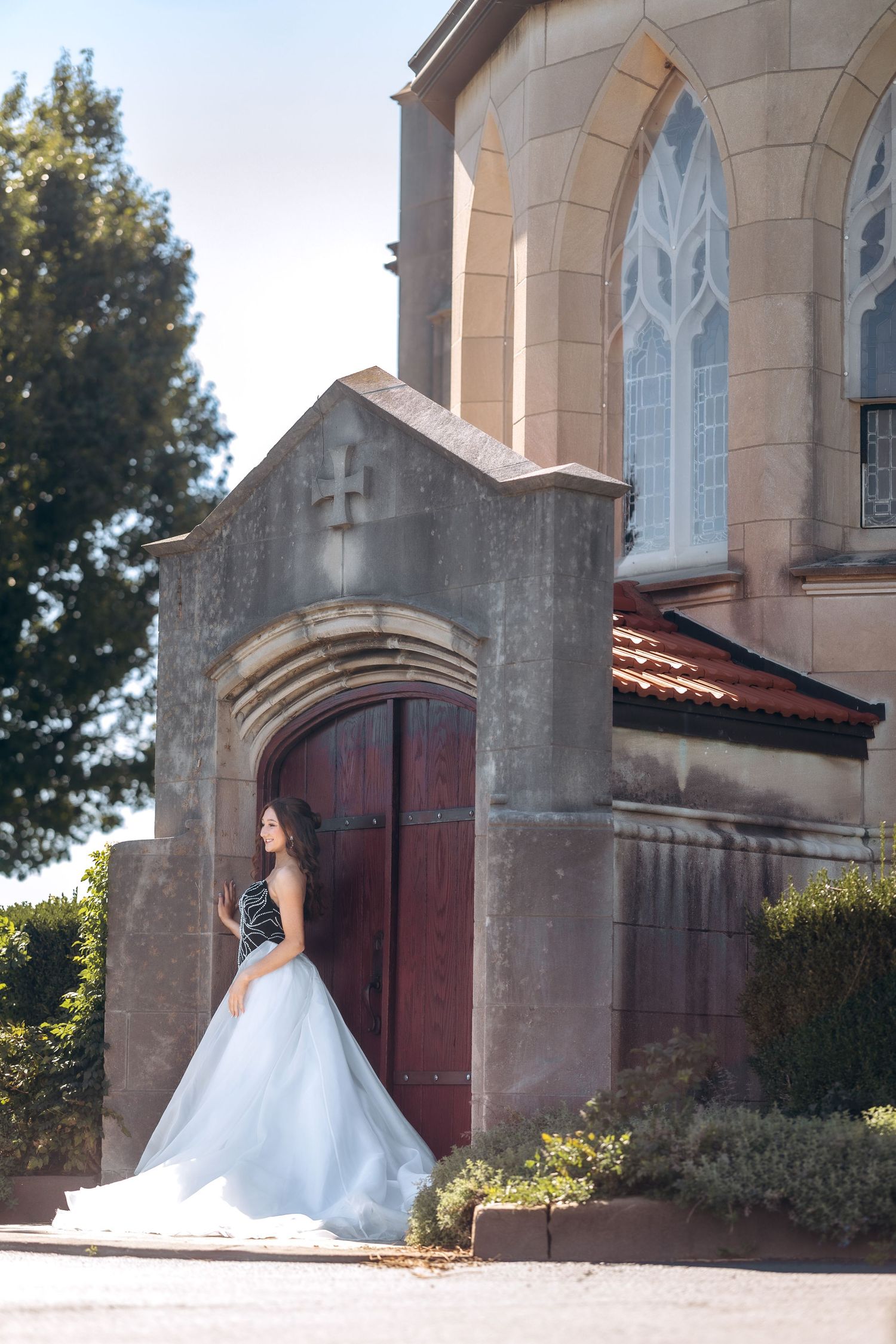 A classic white wedding dress photographed against a historic church exterior.