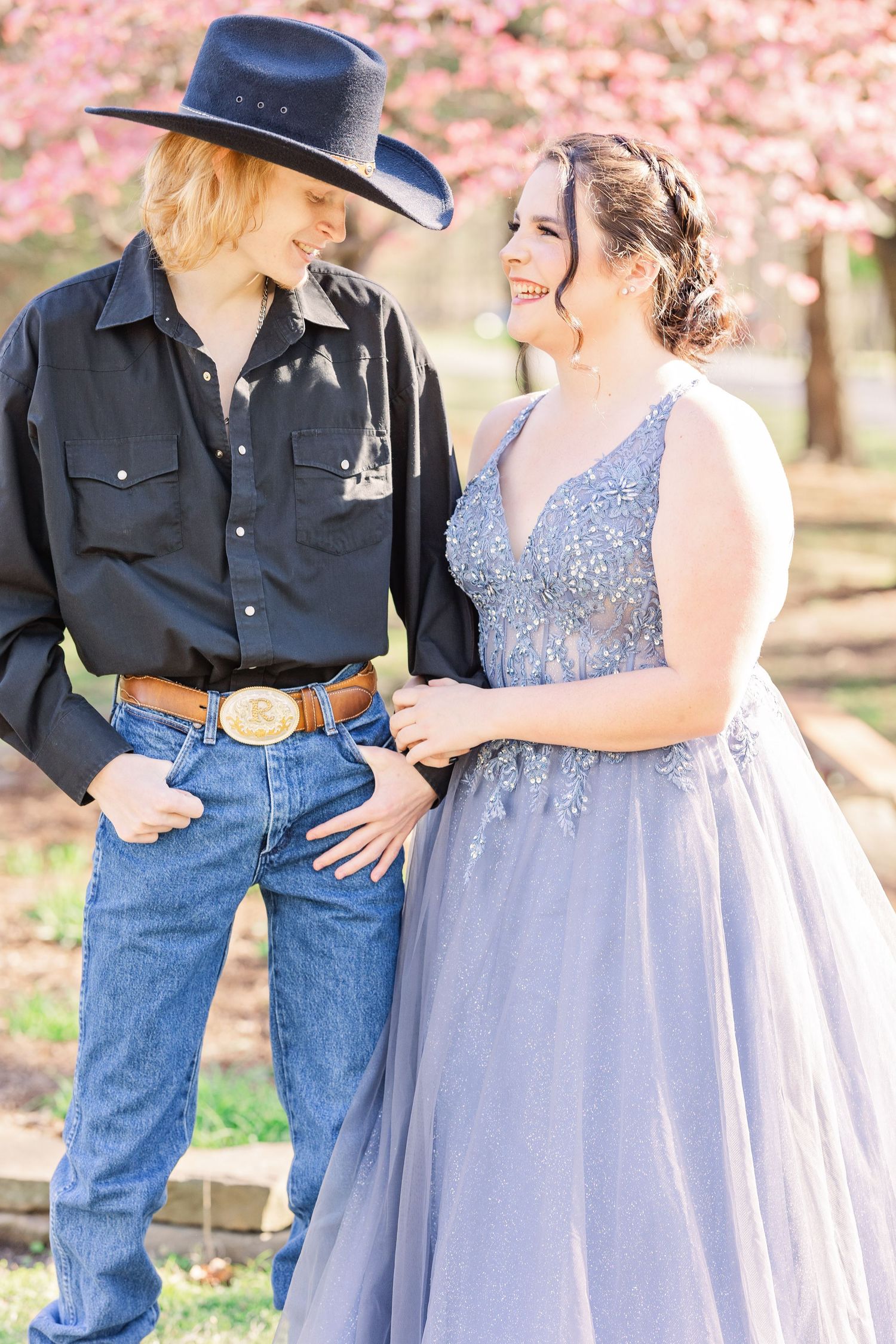 Romantic couple photos under cherry blossoms with person wearing sparkly lavender dress.
