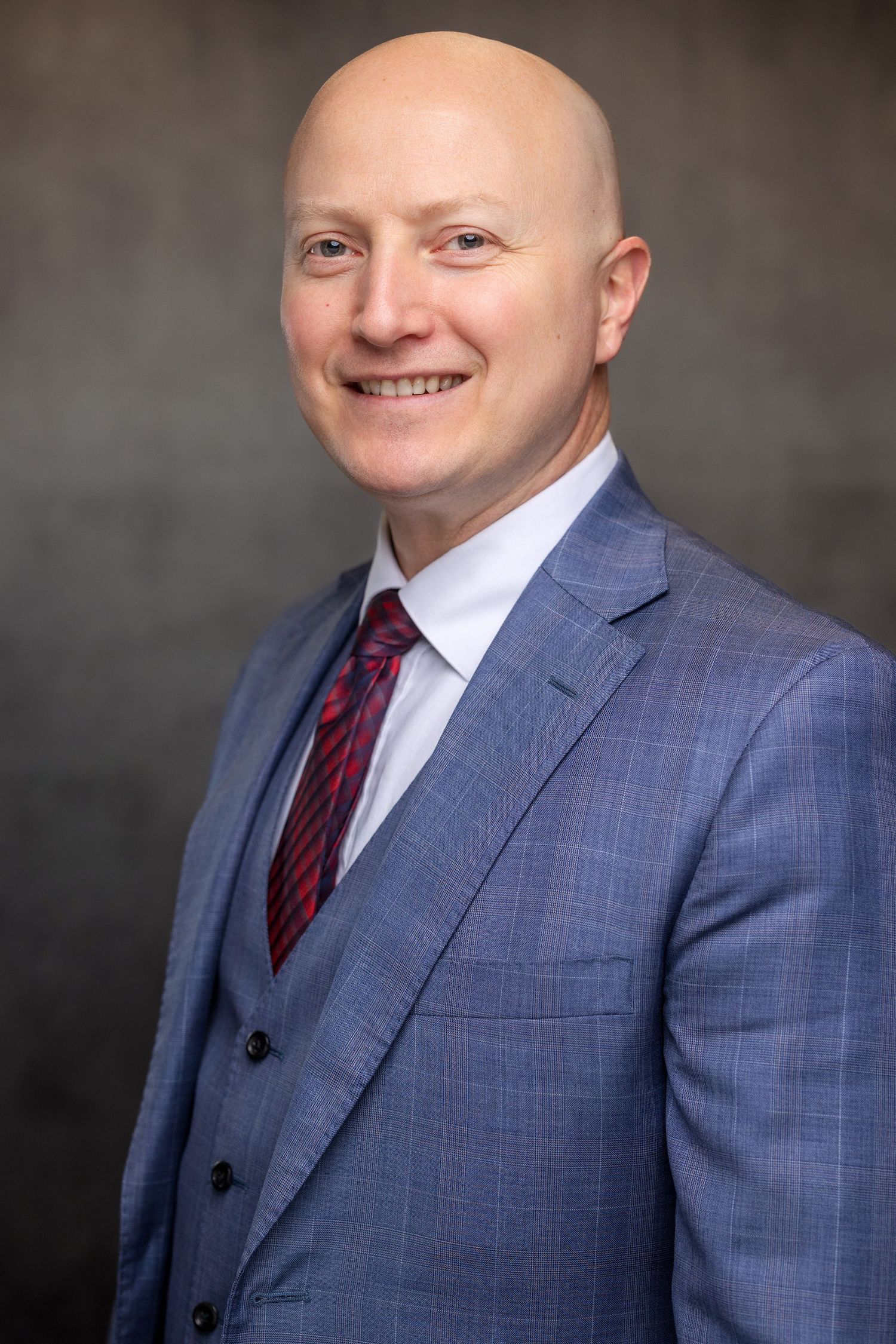 Business headshot sequence showing person in gray plaid suit with burgundy tie.