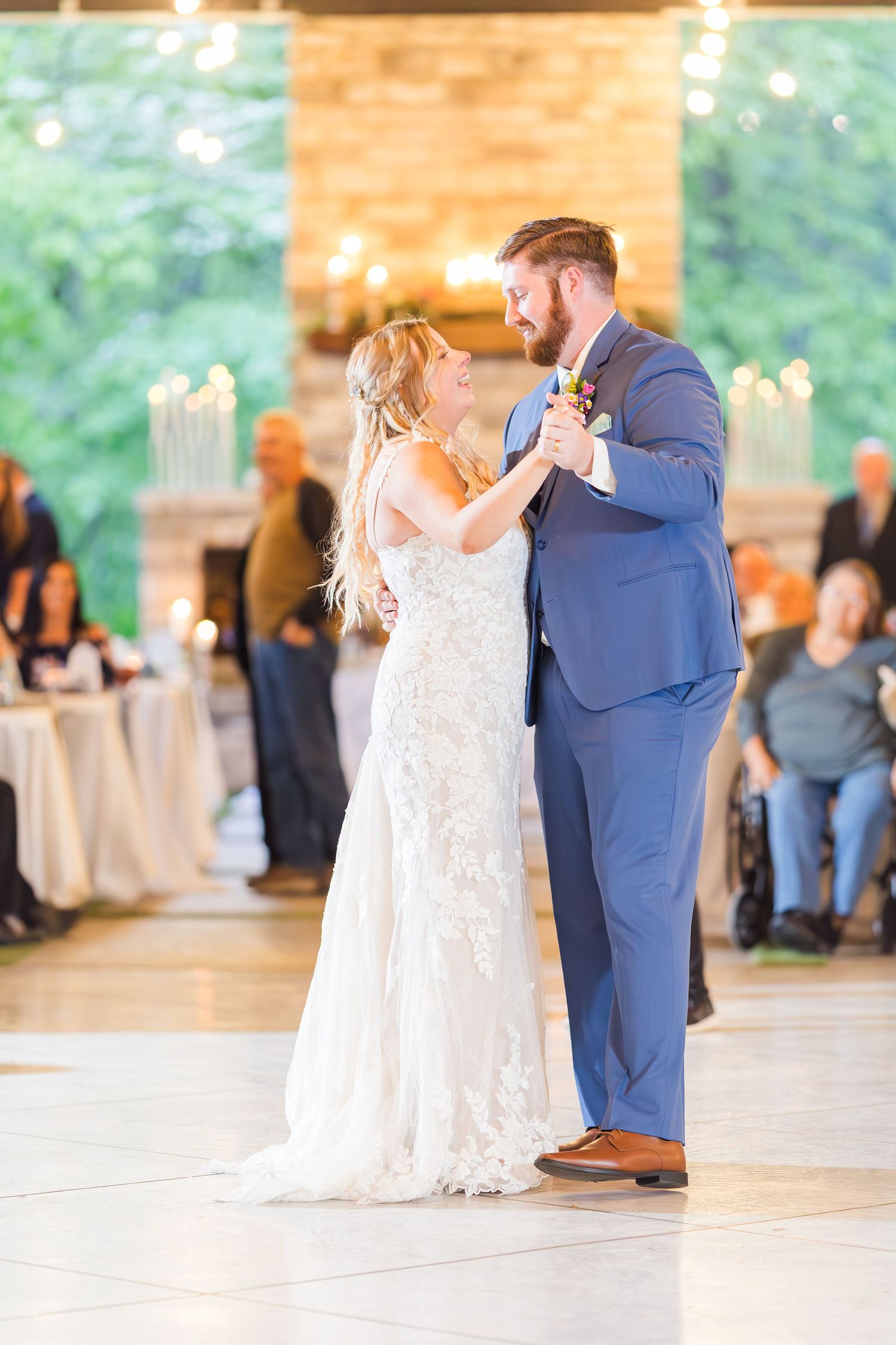 Bride and groom share their first dance in an elegant reception hall with large windows.