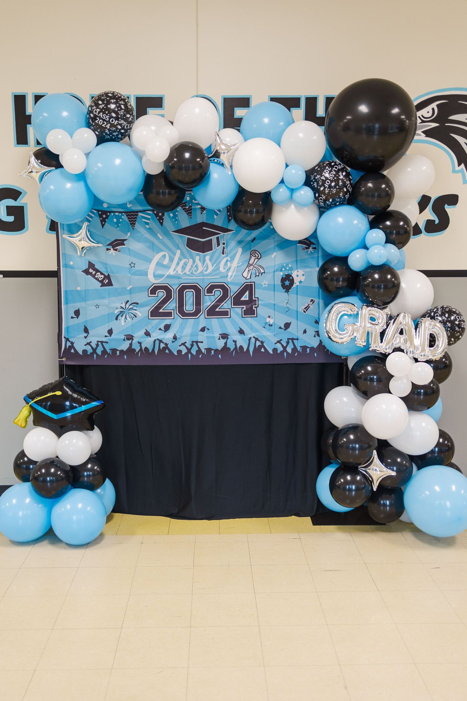 Class of 2024 graduation banner with blue, white and black balloon arch display.