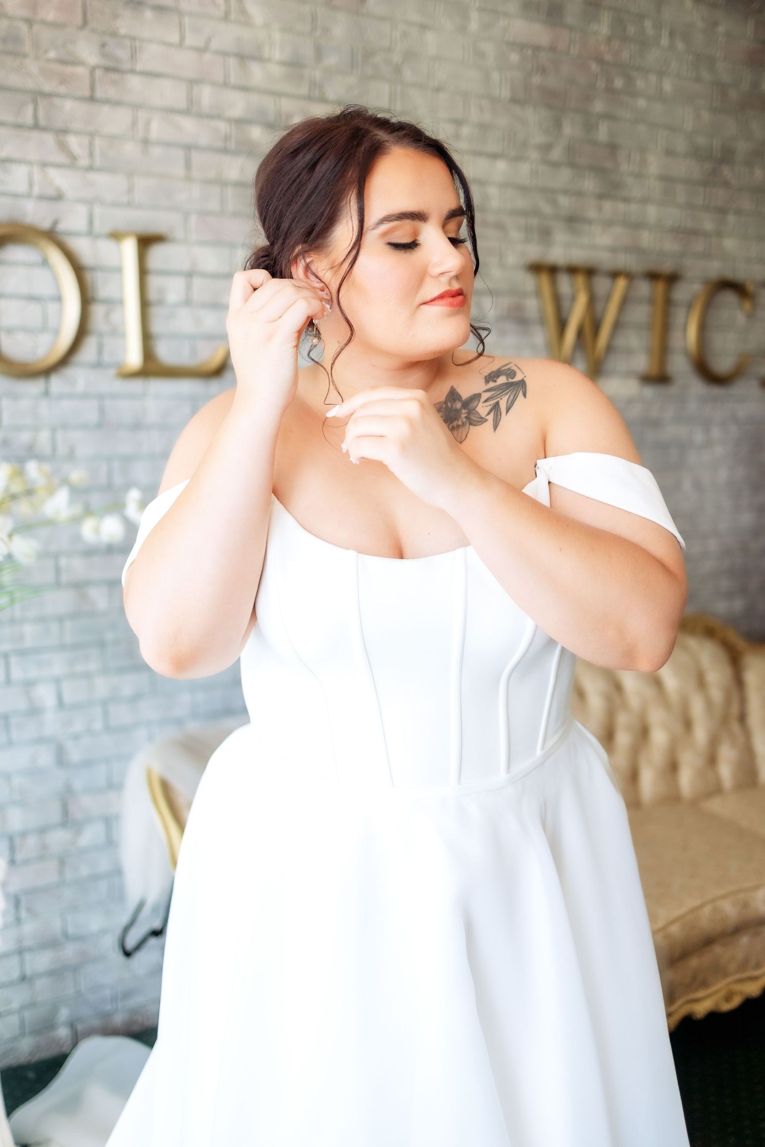 Getting ready scene with white bridal robe against painted brick wall.