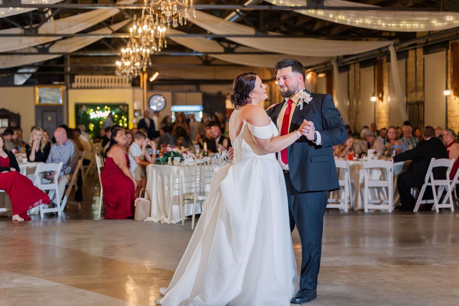 Wedding reception venue decorated with chandeliers and white chairs for celebration.