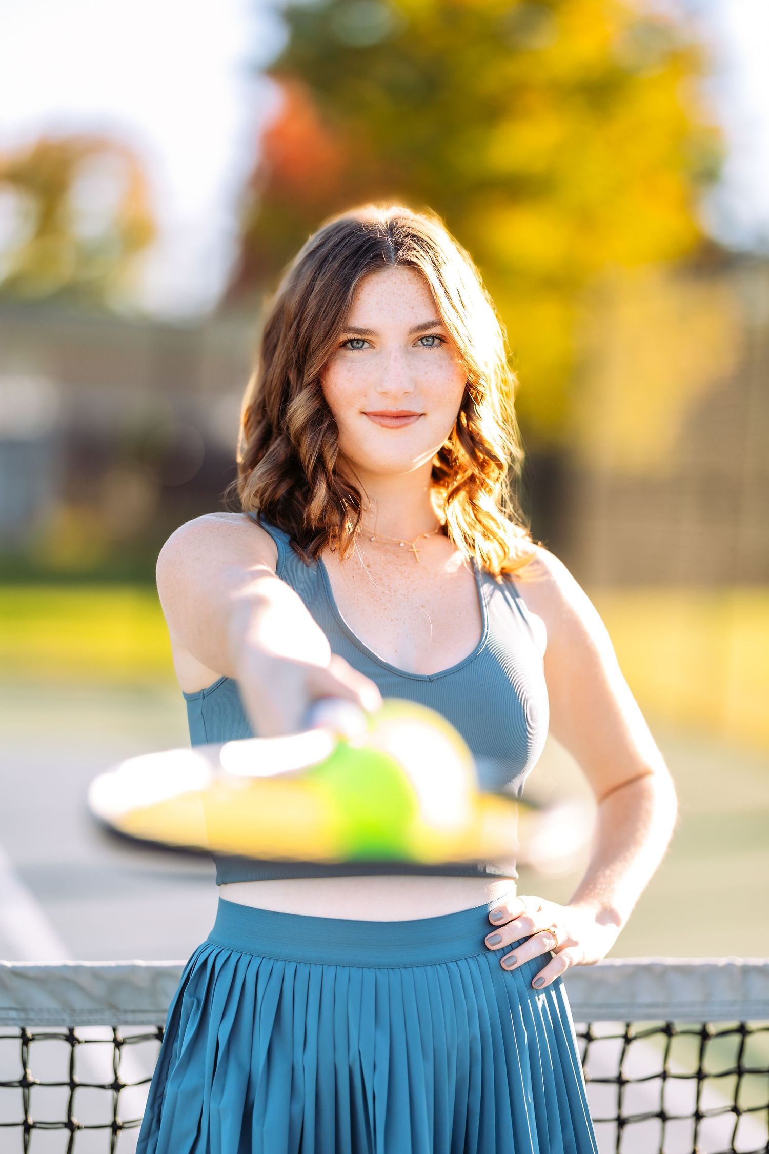 Outdoor portrait session in a teal two-piece outfit against a sunny park background.