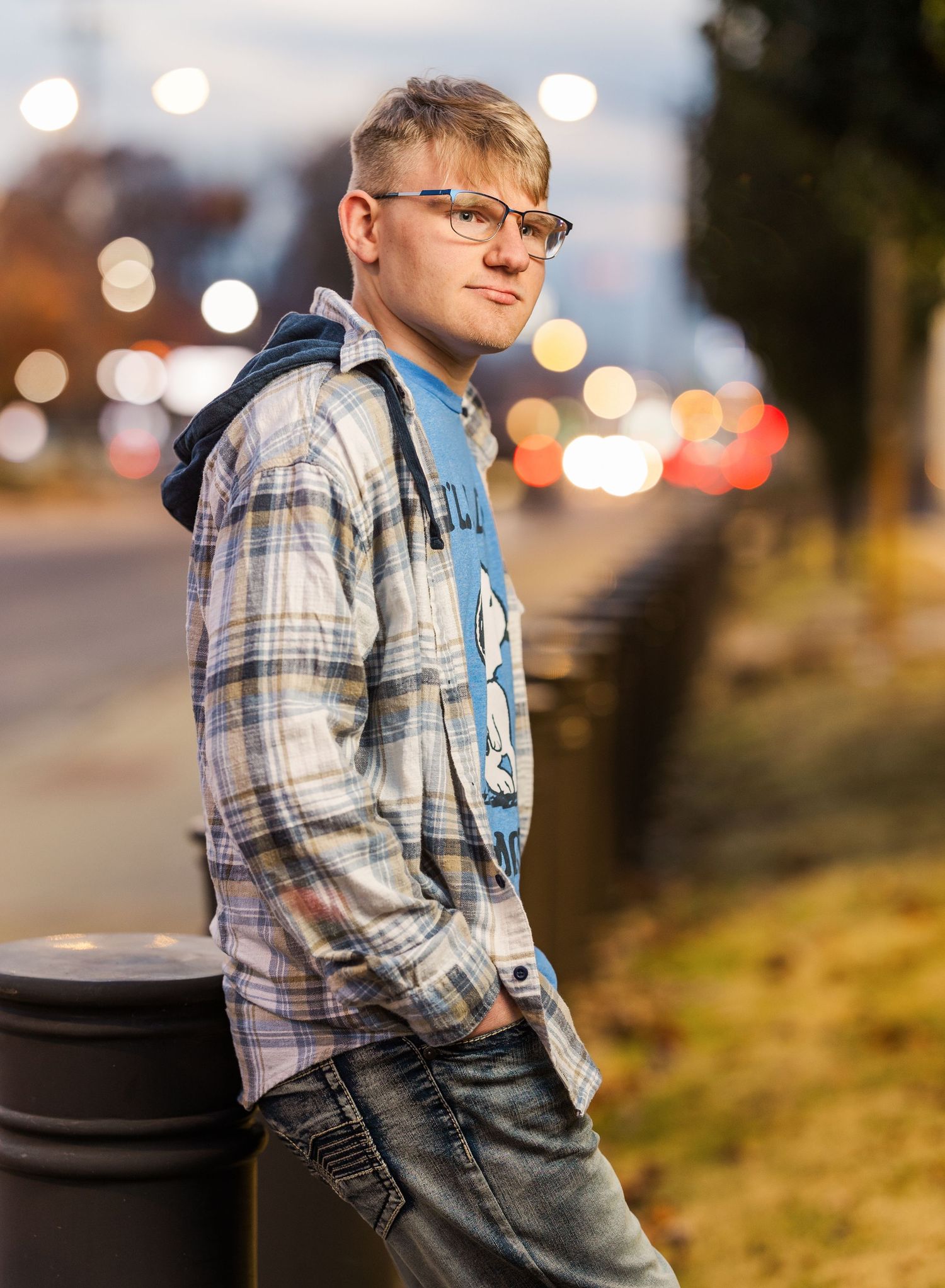 Evening portrait in plaid shirt against bokeh city lights.