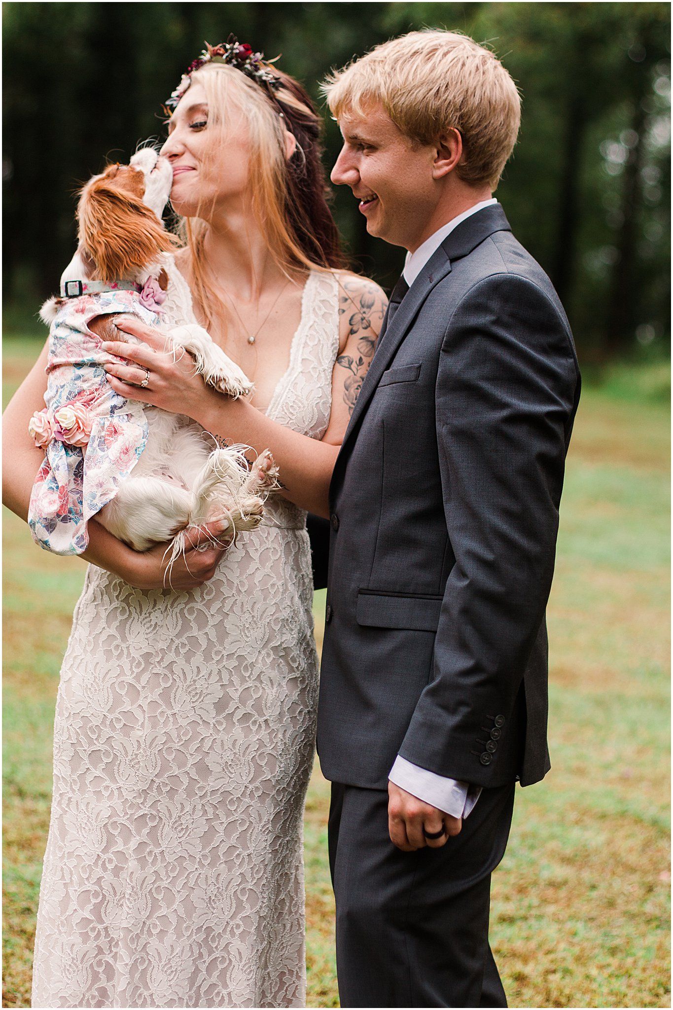 Wedding couple shares tender moment with their small dog wearing floral dress.