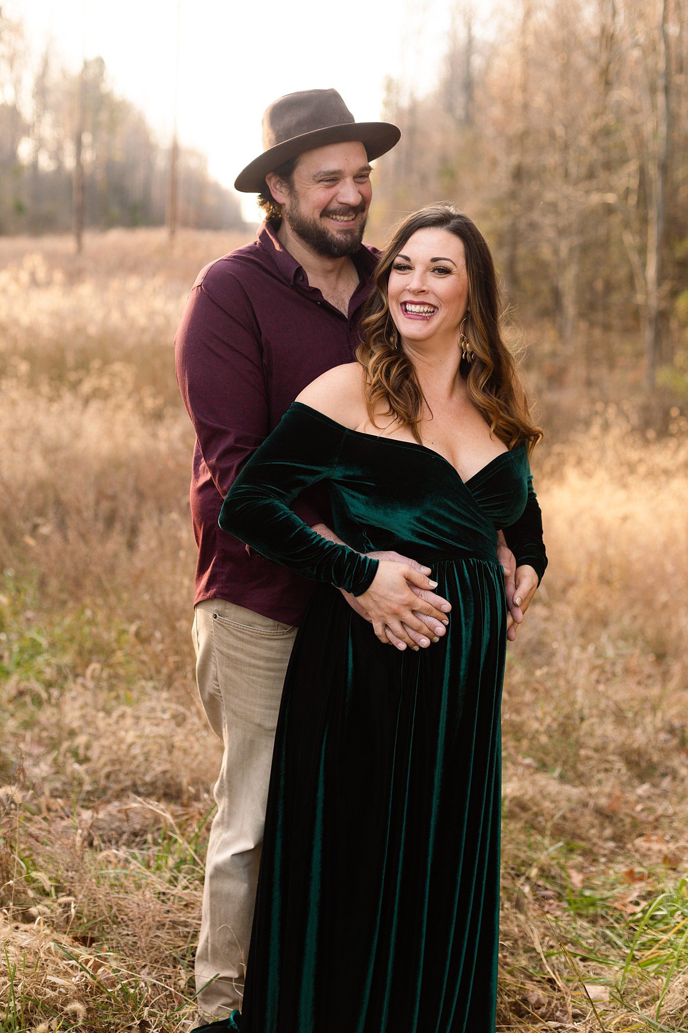 Candid maternity portrait with laughing couple in autumn outdoor setting.
