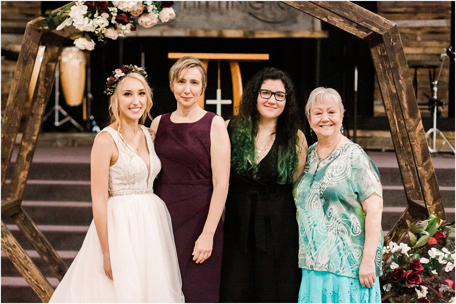 Small group poses together at wedding venue with rustic wooden backdrop.