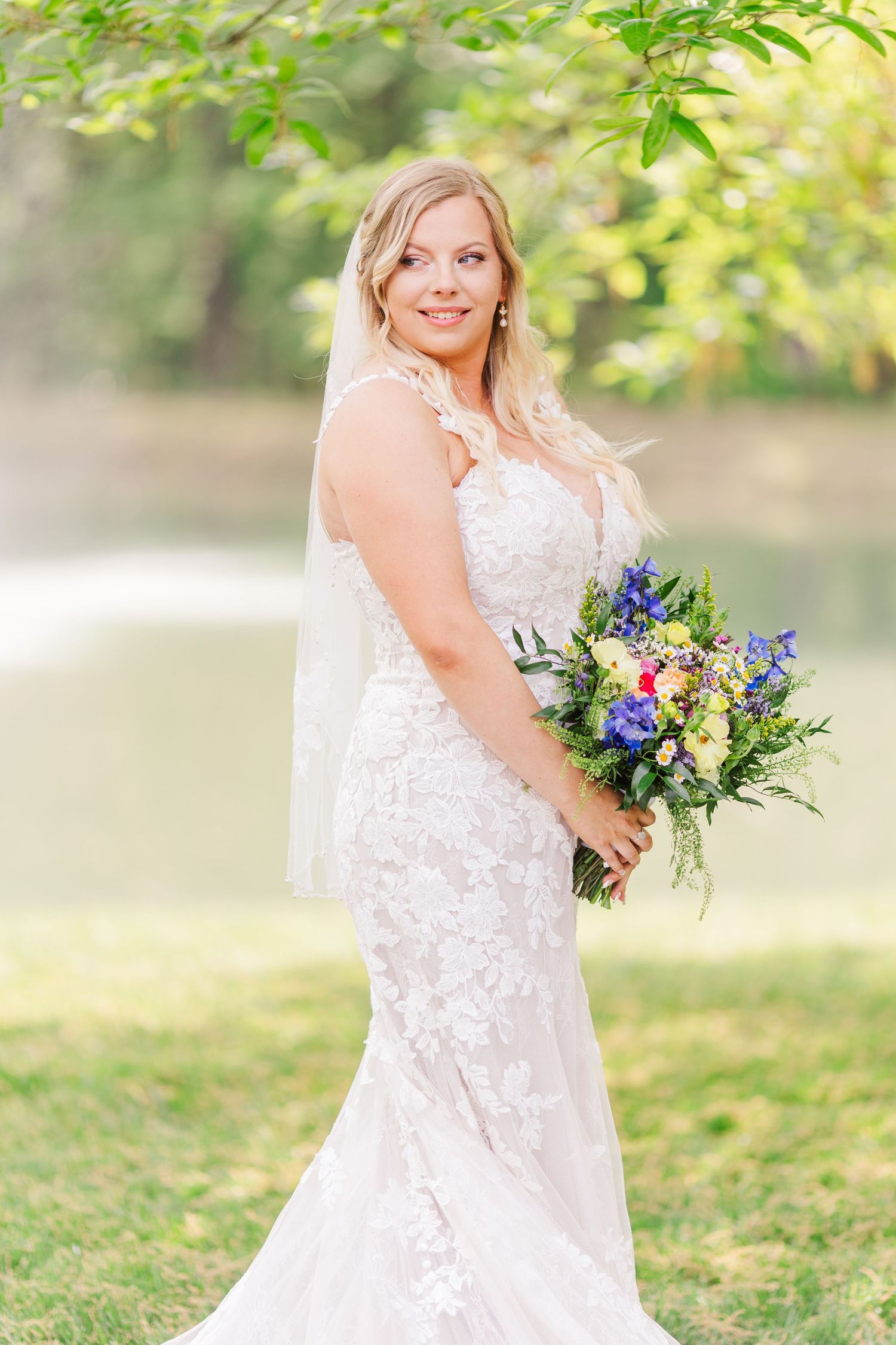 Outdoor bridal portraits featuring lace gown and vibrant blue and purple bouquet.