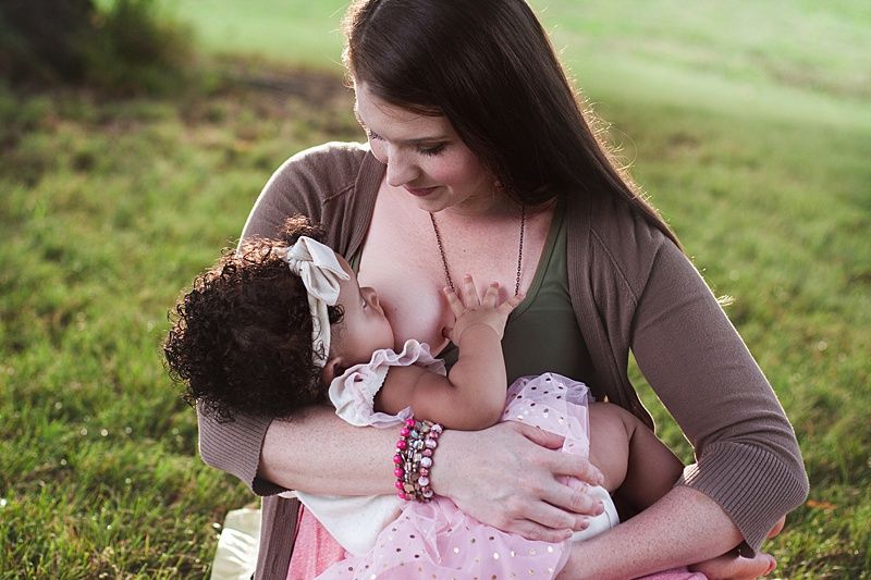 Natural breastfeeding photograph taken in a peaceful outdoor setting.