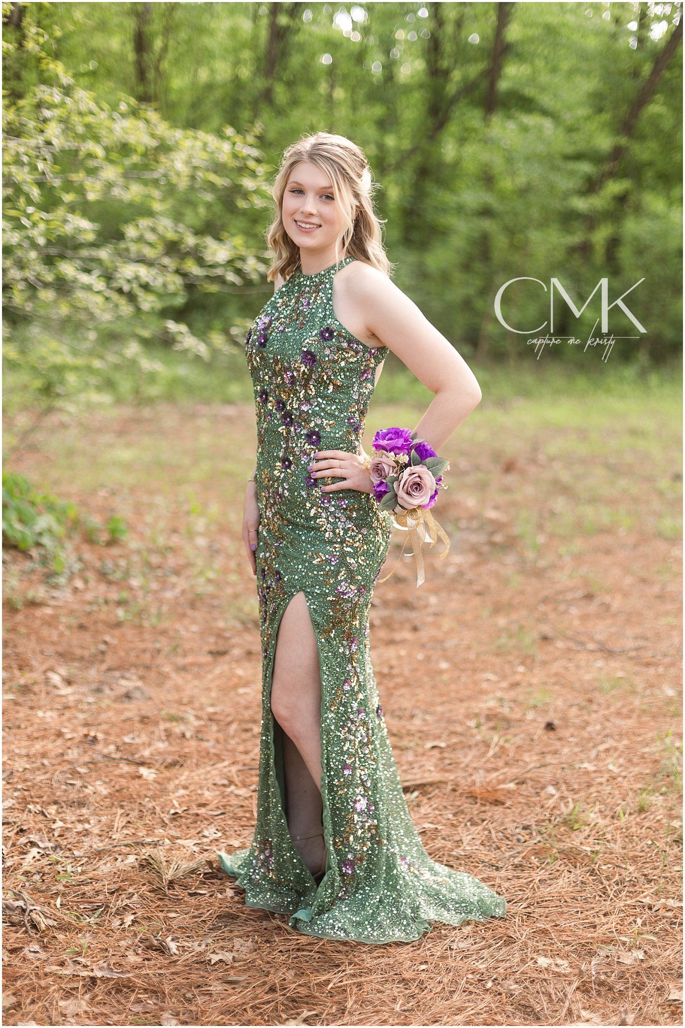 A sparkly green evening gown with thigh slit and halter neckline photographed in a forest setting.