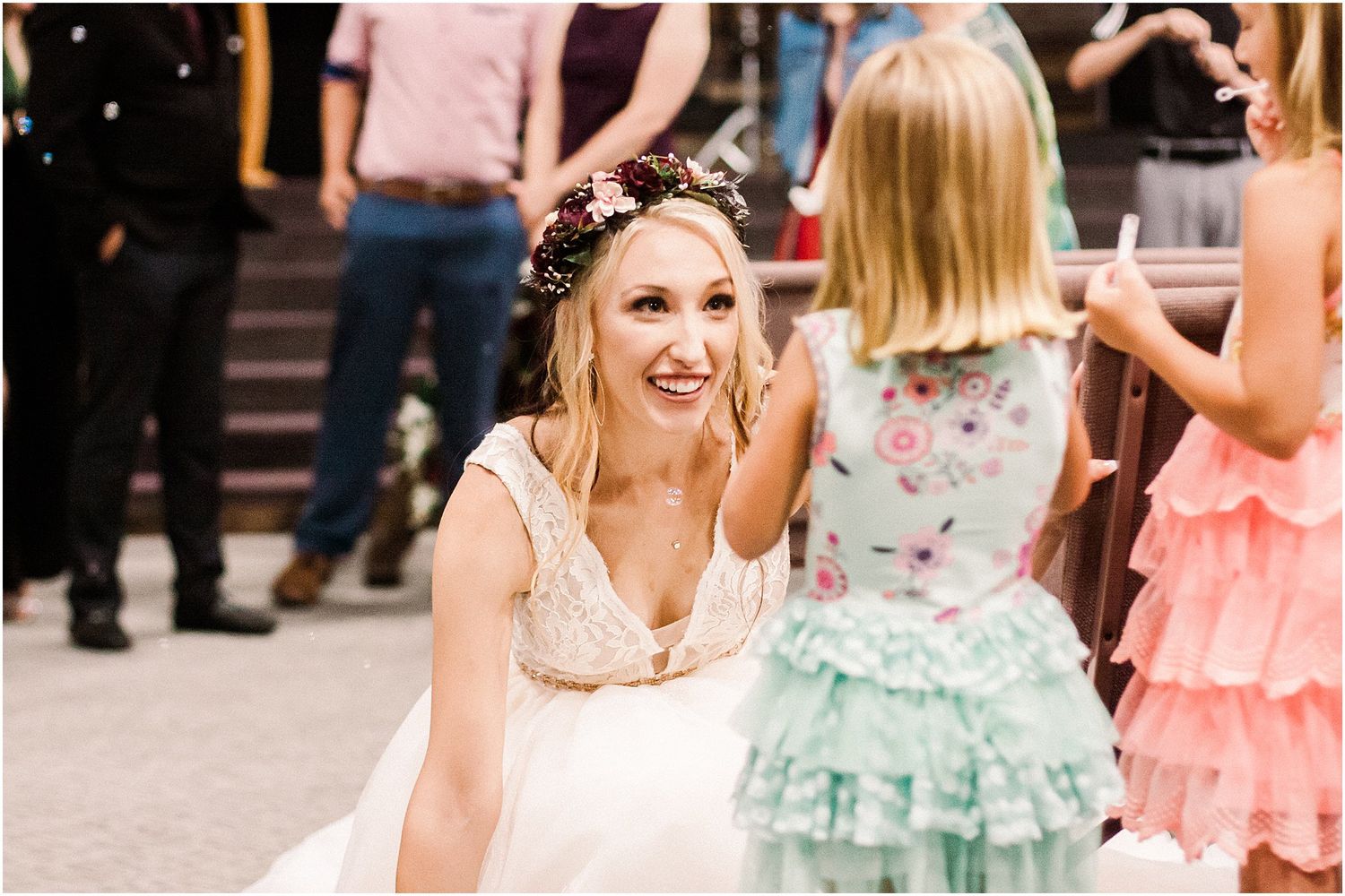 Bride in white dress and floral crown smiling during wedding reception celebrations.