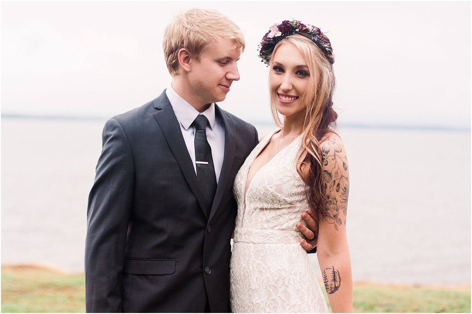 Newlyweds share a romantic moment outdoors by the water on their wedding day.