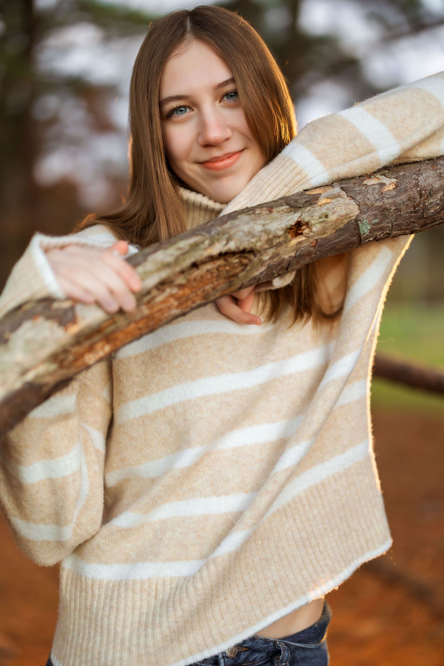 Person in striped sweater playfully posing with tree branch.