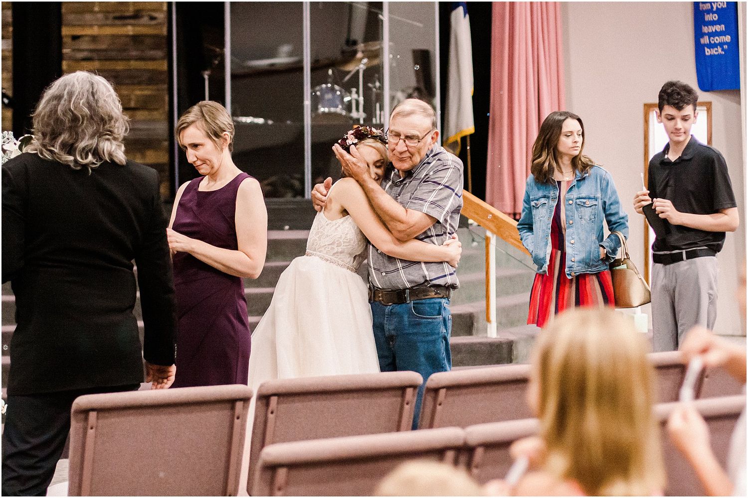 Wedding reception scene with guests mingling outside a rustic venue.
