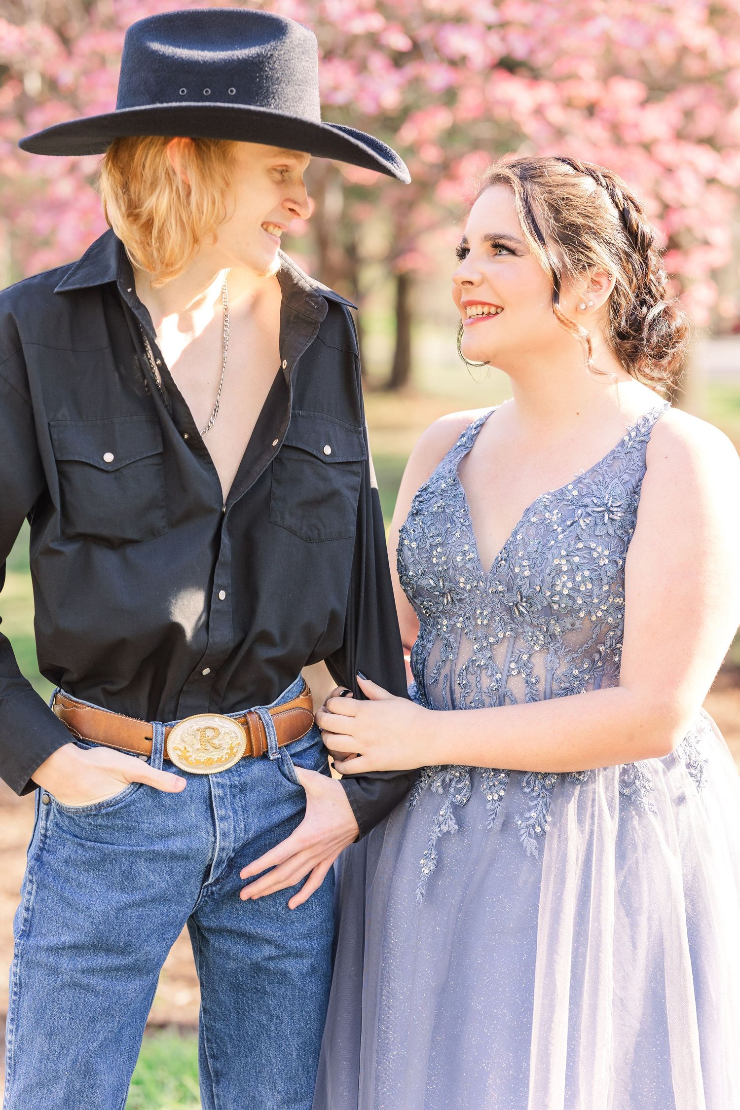 Couple photos with western style outfit and lavender formal dress under pink blossoms.