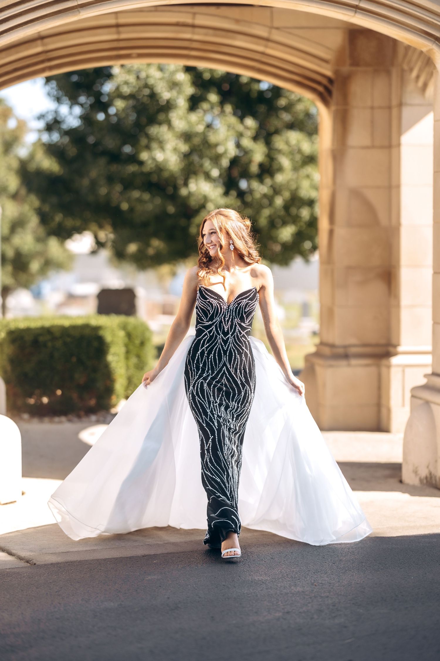 A flowing white dress train photographed under stone archways in natural light.
