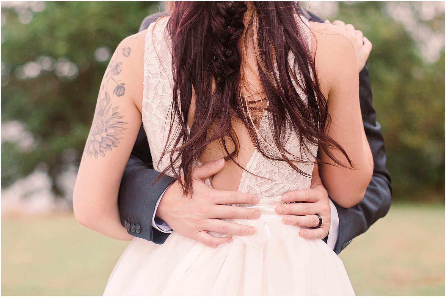 Close-up detail shot showing hands embracing during an outdoor wedding.