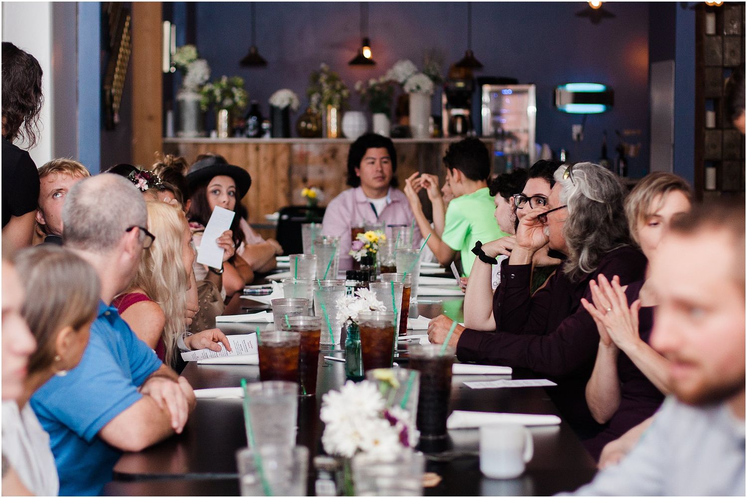 Long restaurant table setup with guests sitting and socializing during an event.