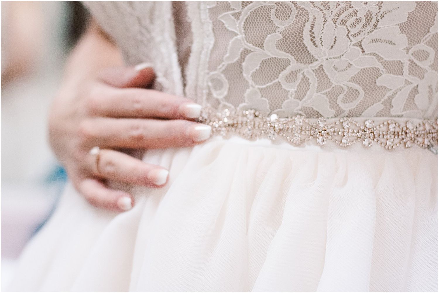 Close-up of intricate beaded belt detail on white wedding dress with lace bodice.