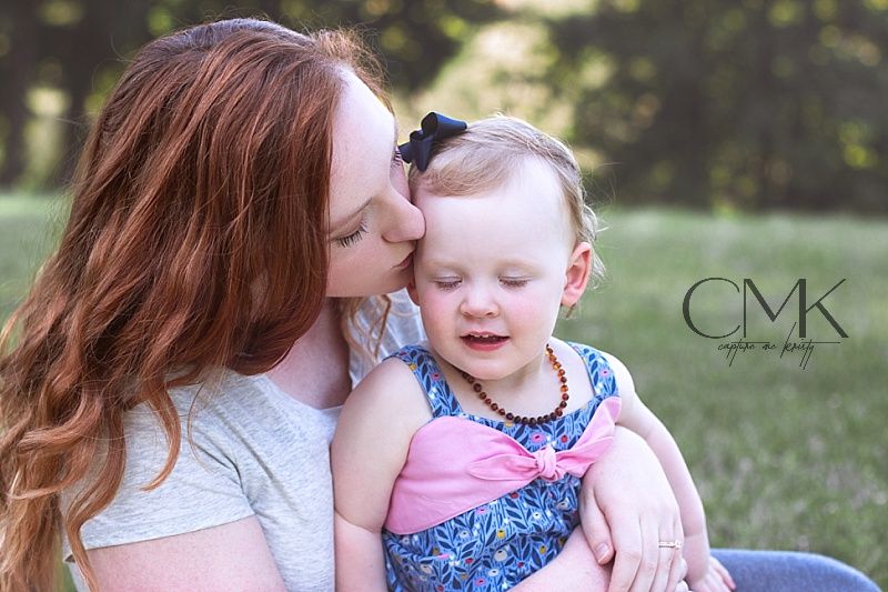 A tender outdoor portrait of a loving embrace between parent and child in a sunny garden setting.
