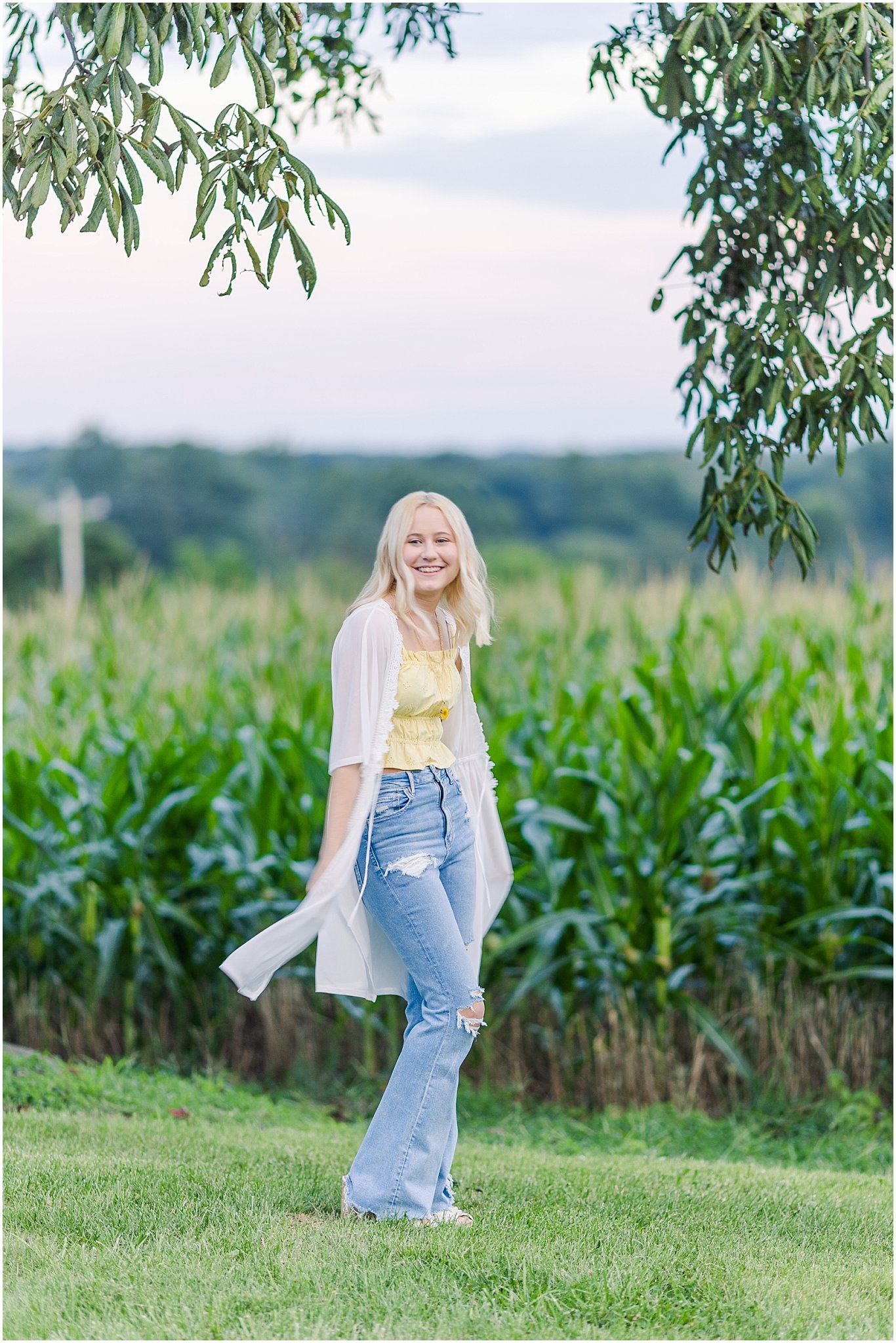 Senior girl in front of a corn field at sunset