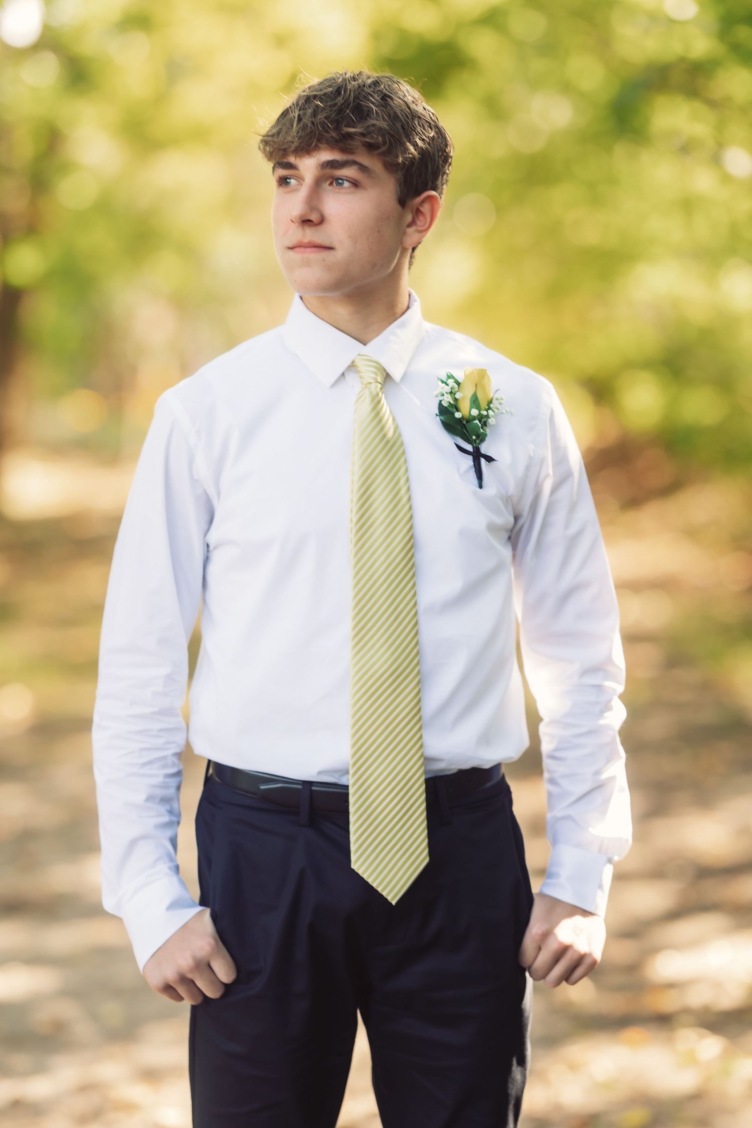 Young attendant in white shirt and striped tie poses for formal portraits.
