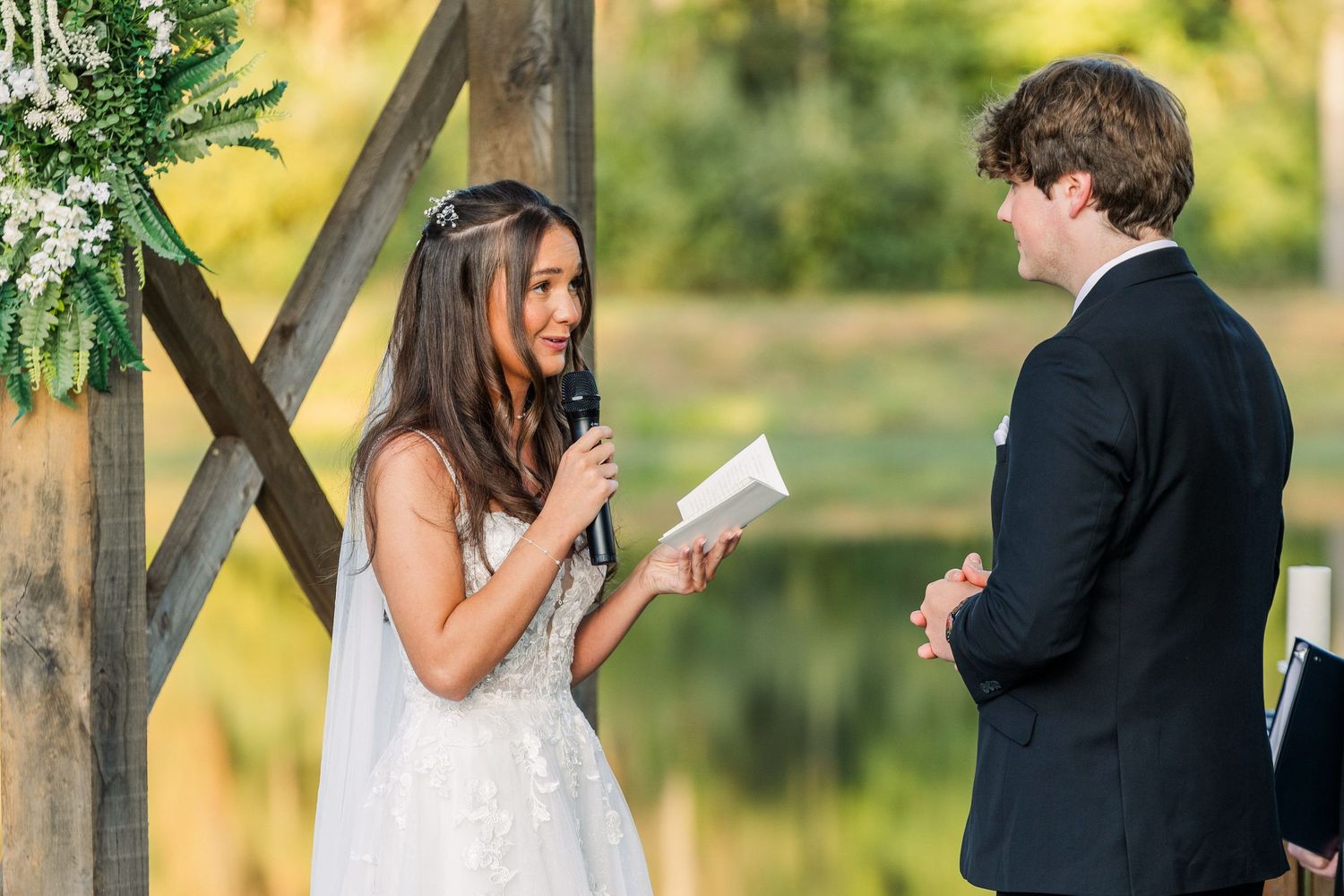 Emotional wedding ceremony moment captured under wooden pavilion at sunset.