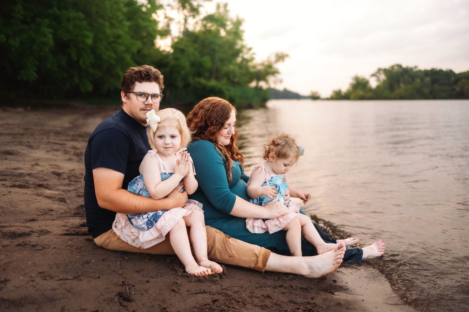 A group relaxes together on a sandy beach at sunset during a casual photo session.
