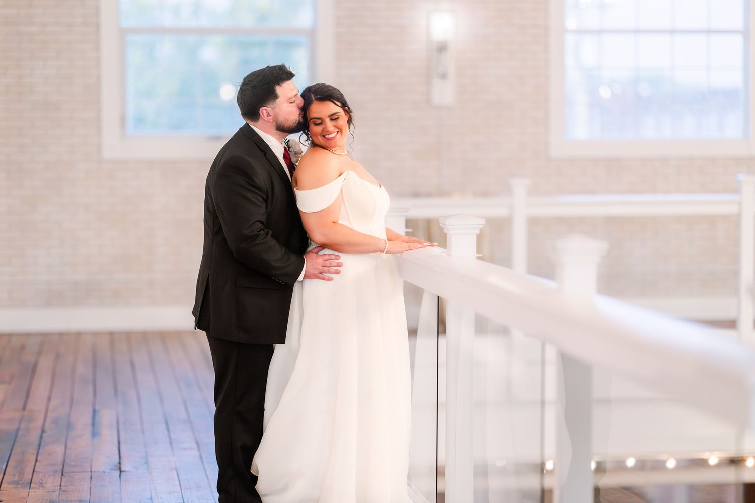 Couple shares intimate moments during their wedding photo session in a bright indoor venue.