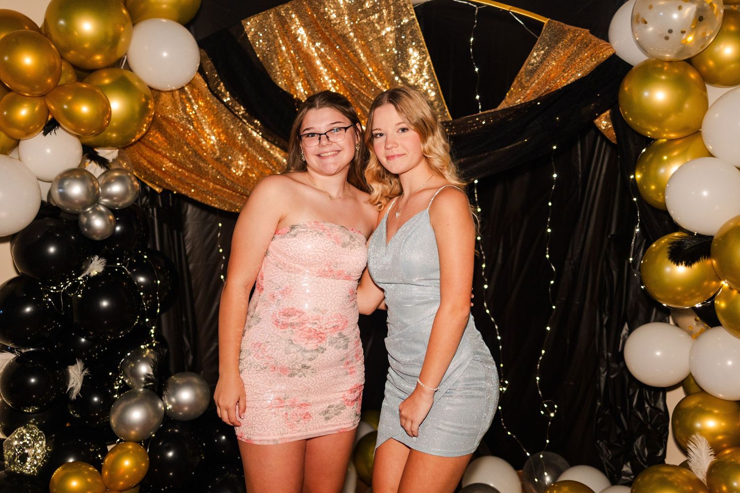 People celebrating at a party with gold and white balloon decorations in the background.
