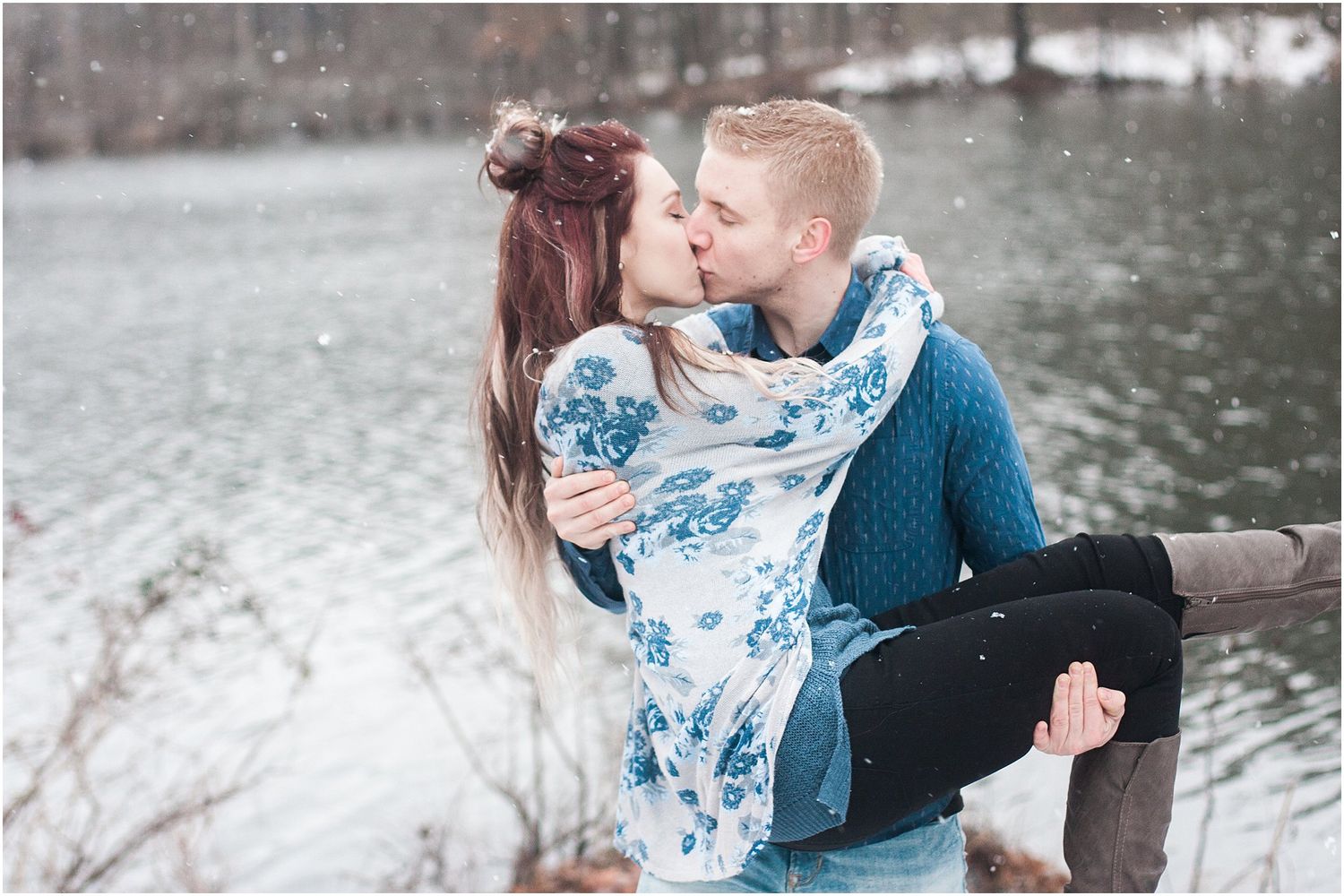 A tender kiss shared during a winter photoshoot by a snowy lake.