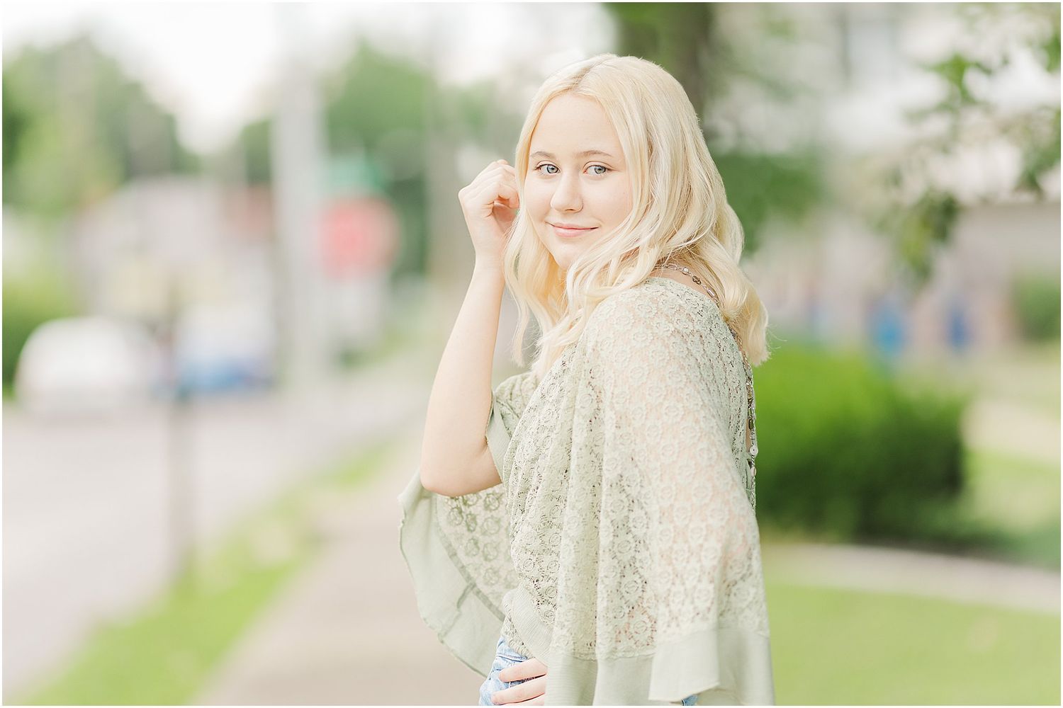 senior girl touches the side of her face while looking back at camera
