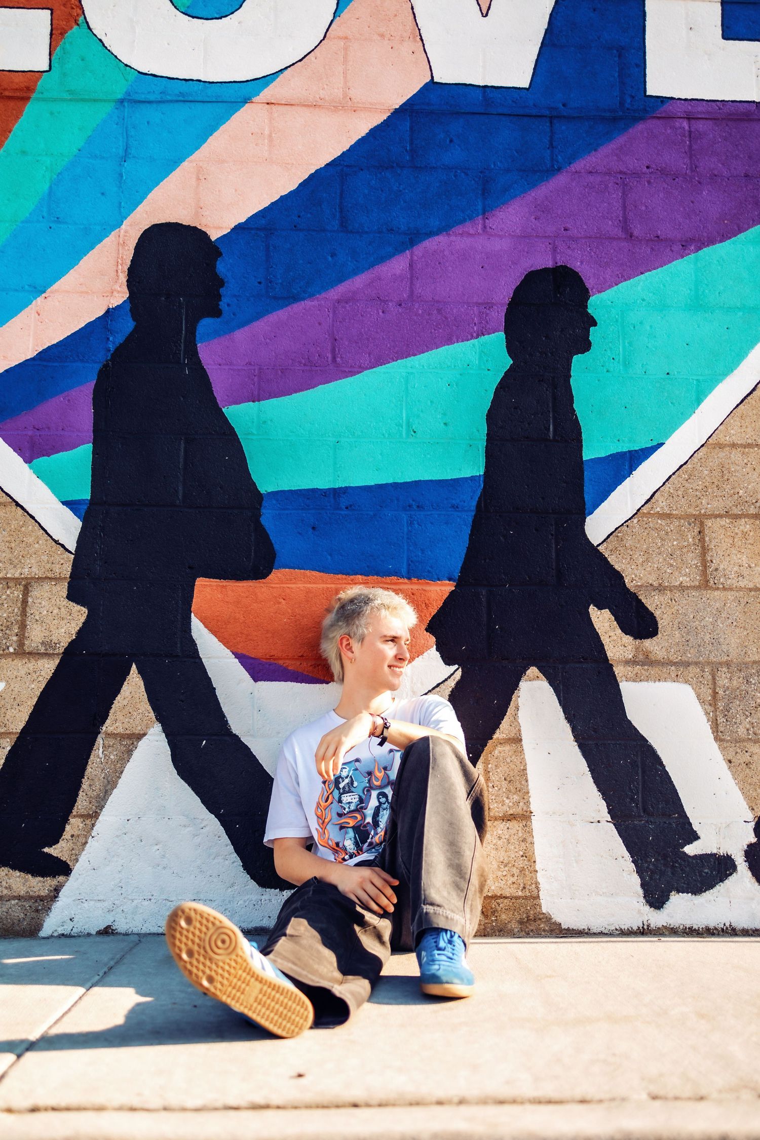 Creative wall mural showing black silhouettes walking against colorful geometric background.