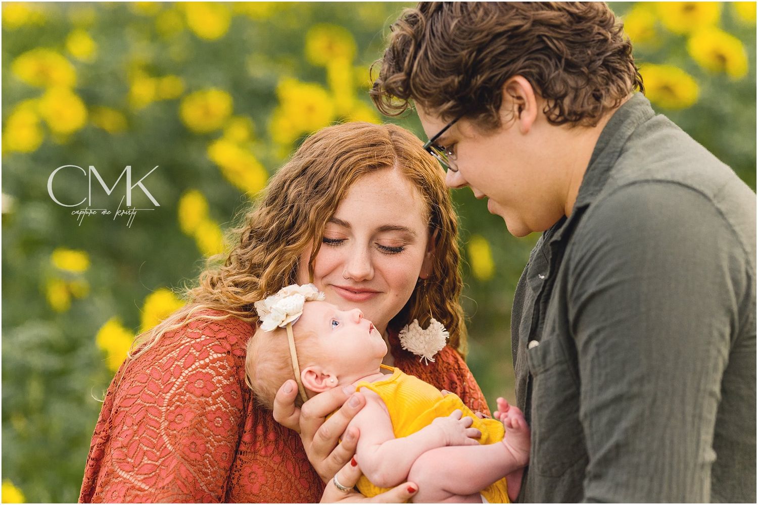 Tender family portrait with baby against backdrop of yellow wildflowers.