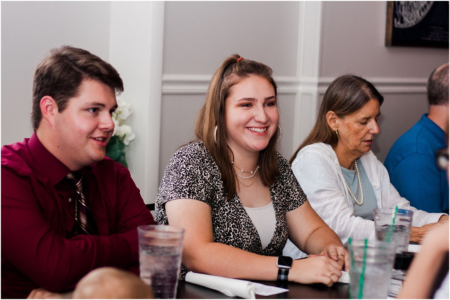 Guests smile and chat during a casual social gathering around a dining table.