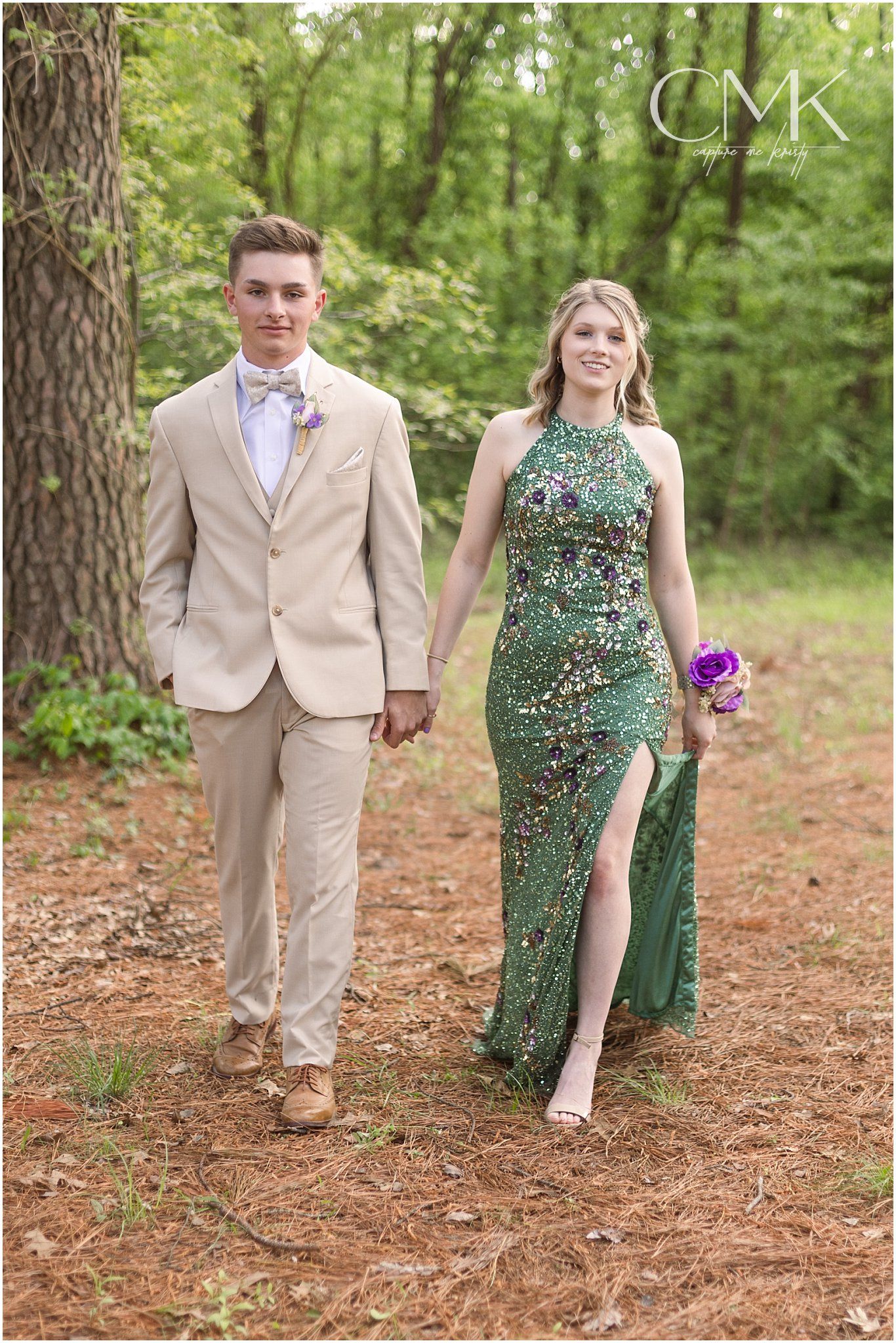 Couple in formal attire walking through a wooded path during a spring photo session.