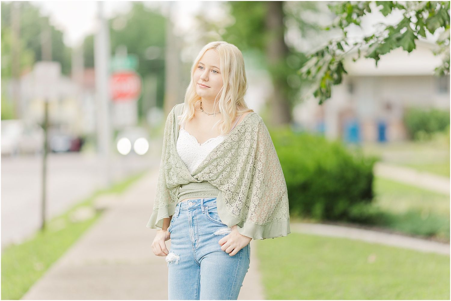 Senior girl looking off camera while standing on sidewalk