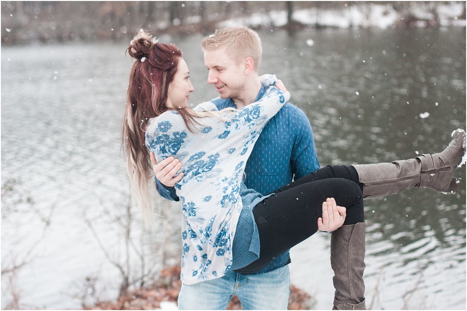 A romantic embrace by a winter lakeside with snow gently falling.
