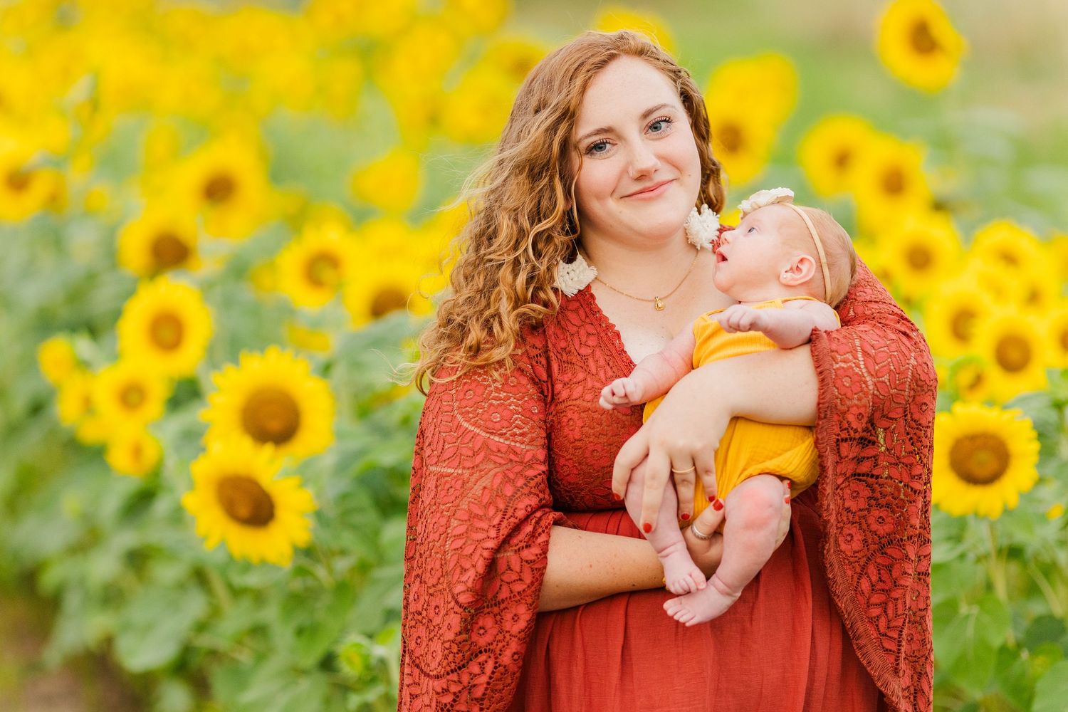 Family portraits taken in a blooming sunflower field with coral-colored attire.