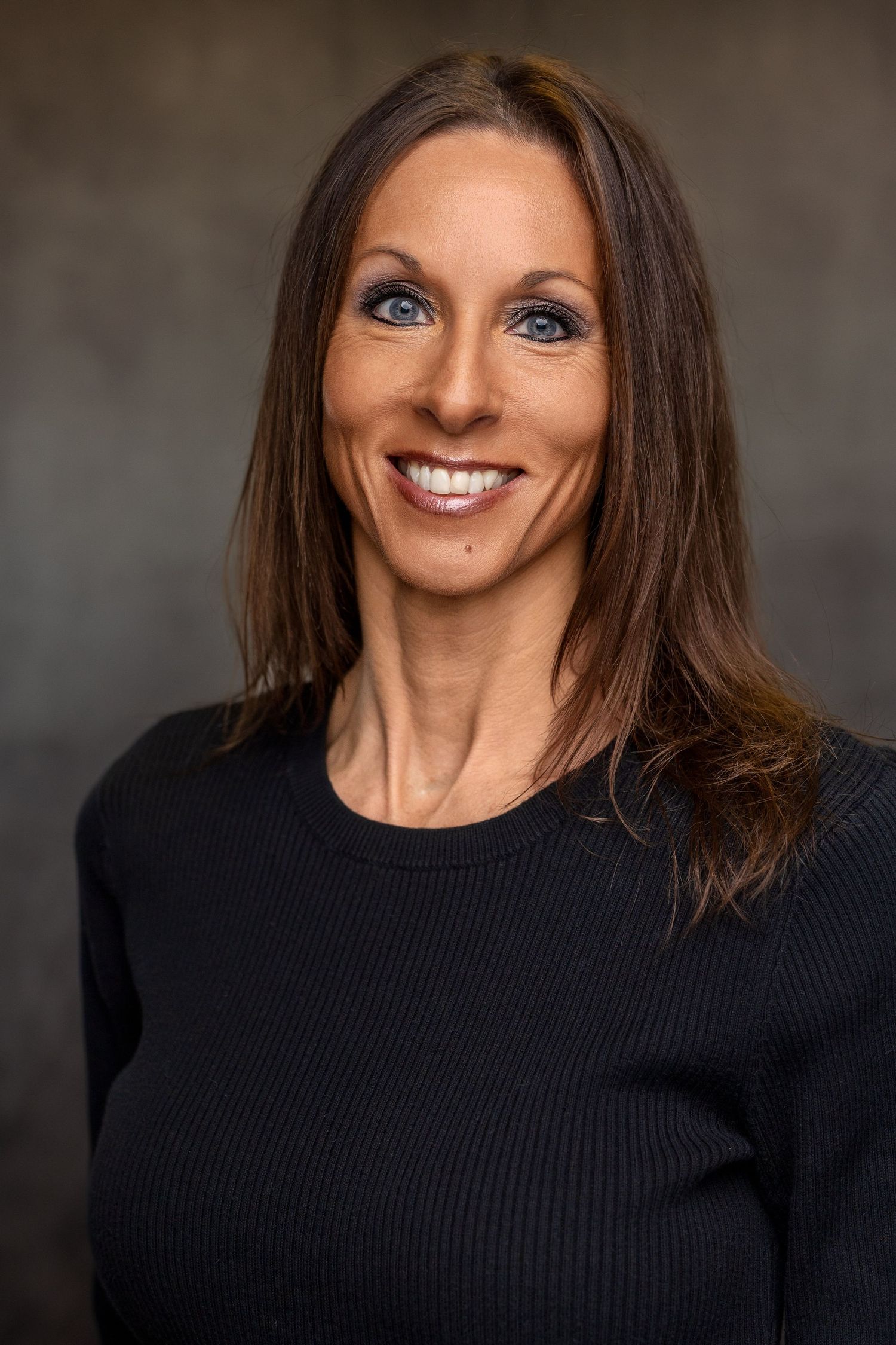 Portrait series showing person in black sweater with bright smile against dark studio background.