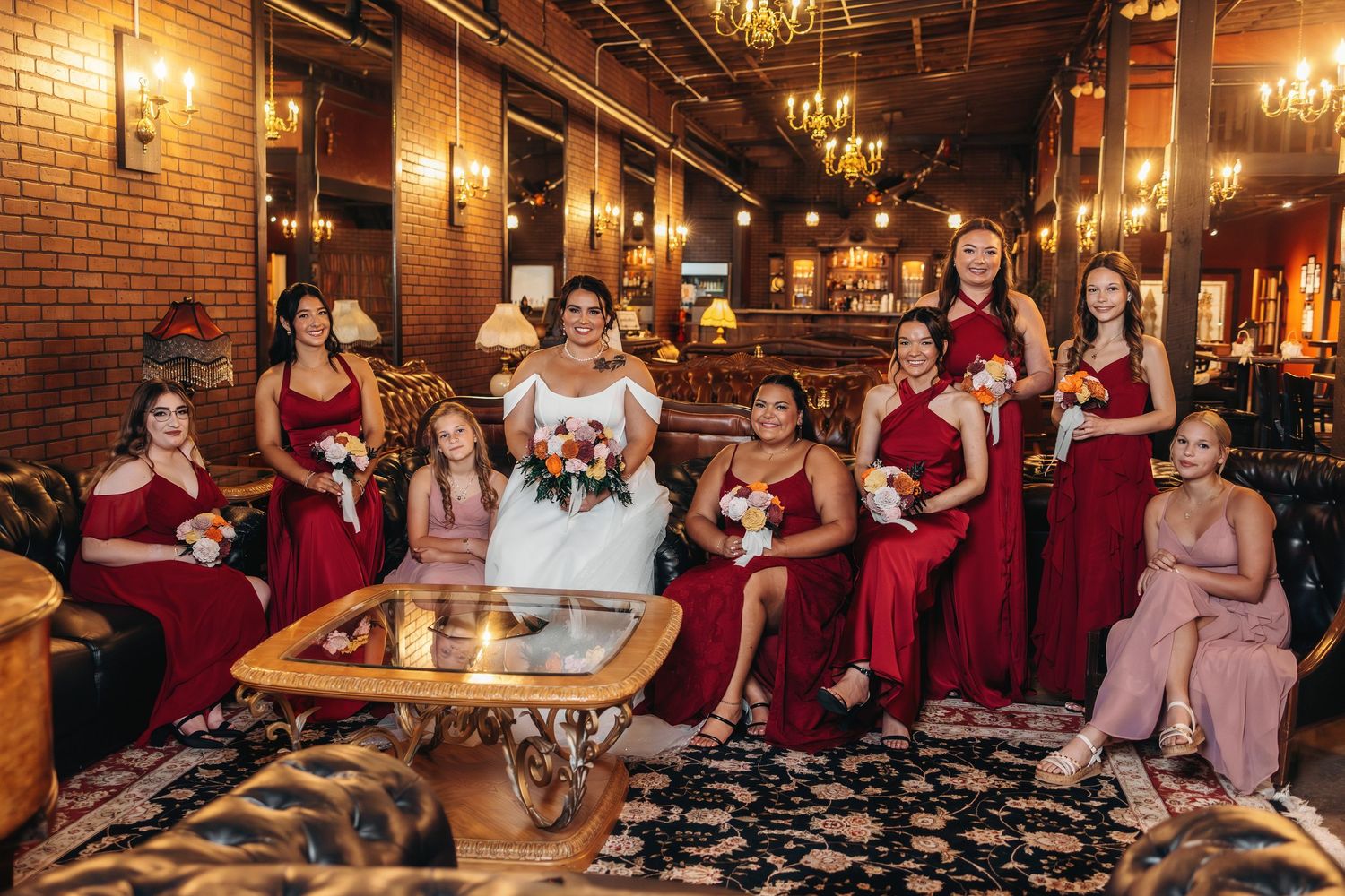 Wedding party celebrates in a rustic venue with exposed brick walls and warm lighting.