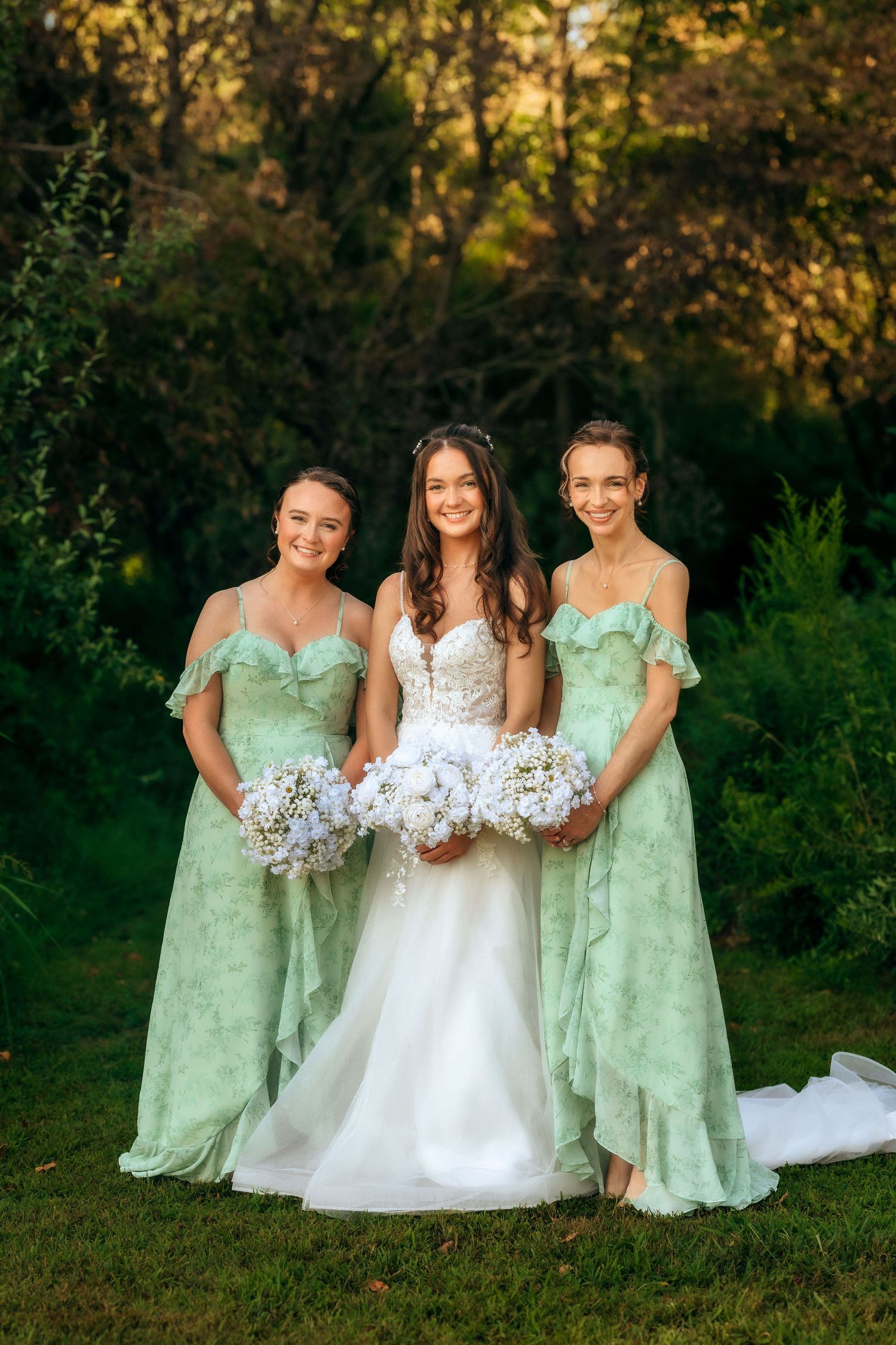 Bride in white gown poses with bridesmaids wearing mint green dresses holding white bouquets.