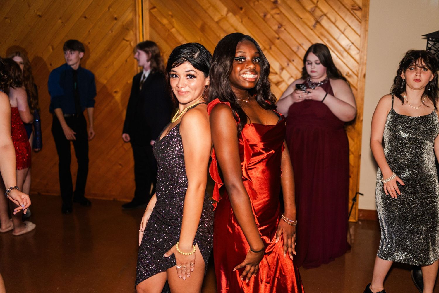 Party attendees in formal dresses gather for group photos at an evening celebration.