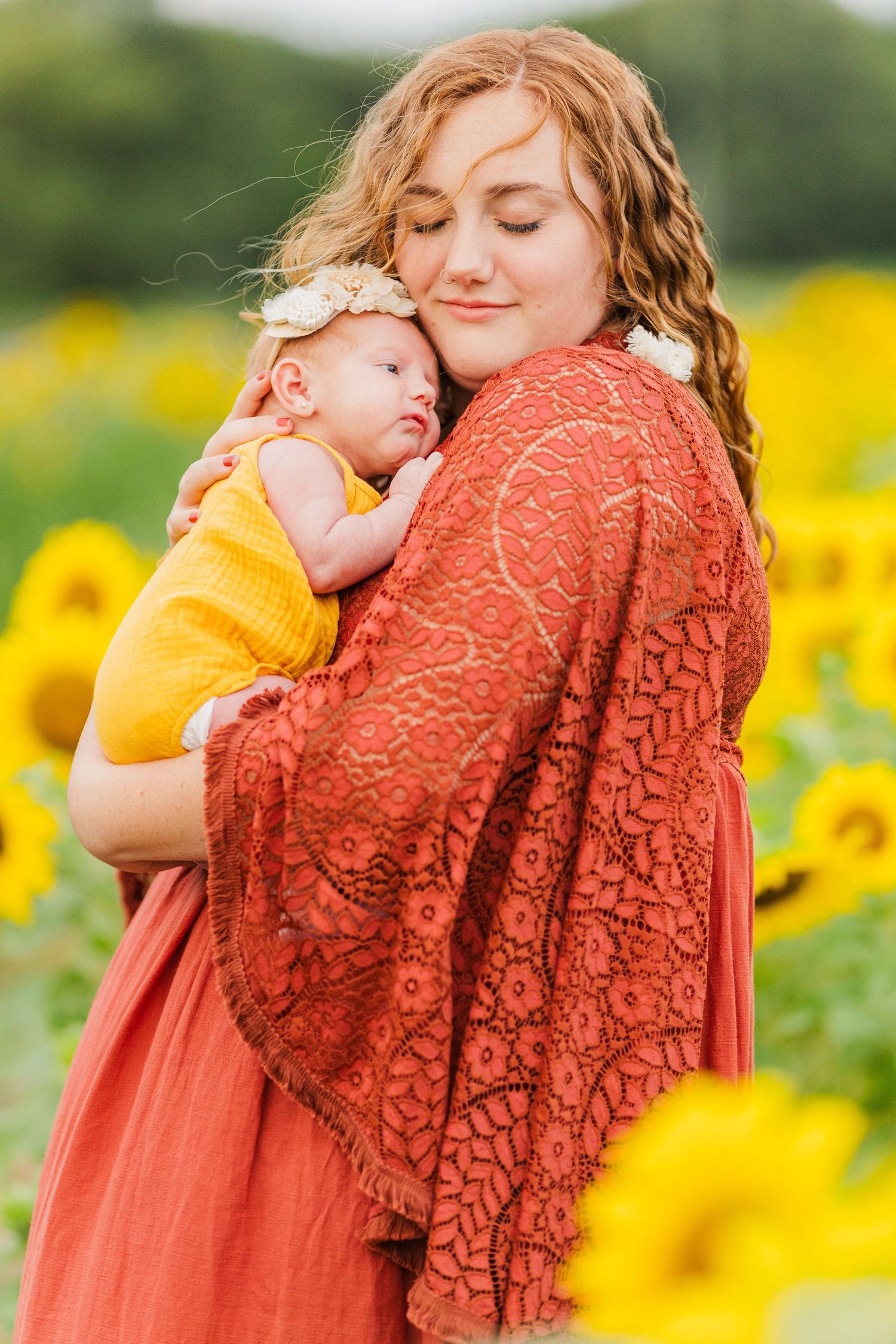 A tender moment captured in a sunflower field with coral lace clothing.