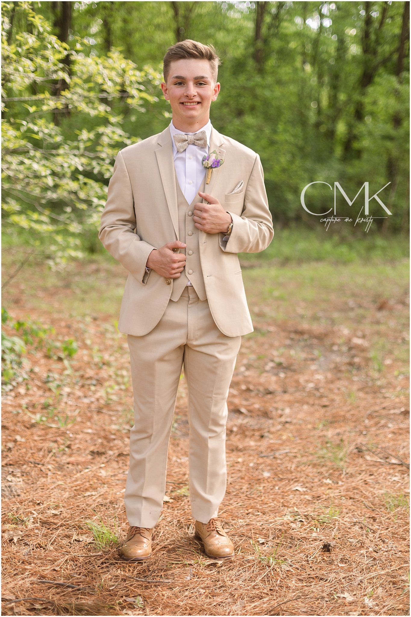 A formal portrait featuring a tan three-piece suit with bow tie in an outdoor setting.