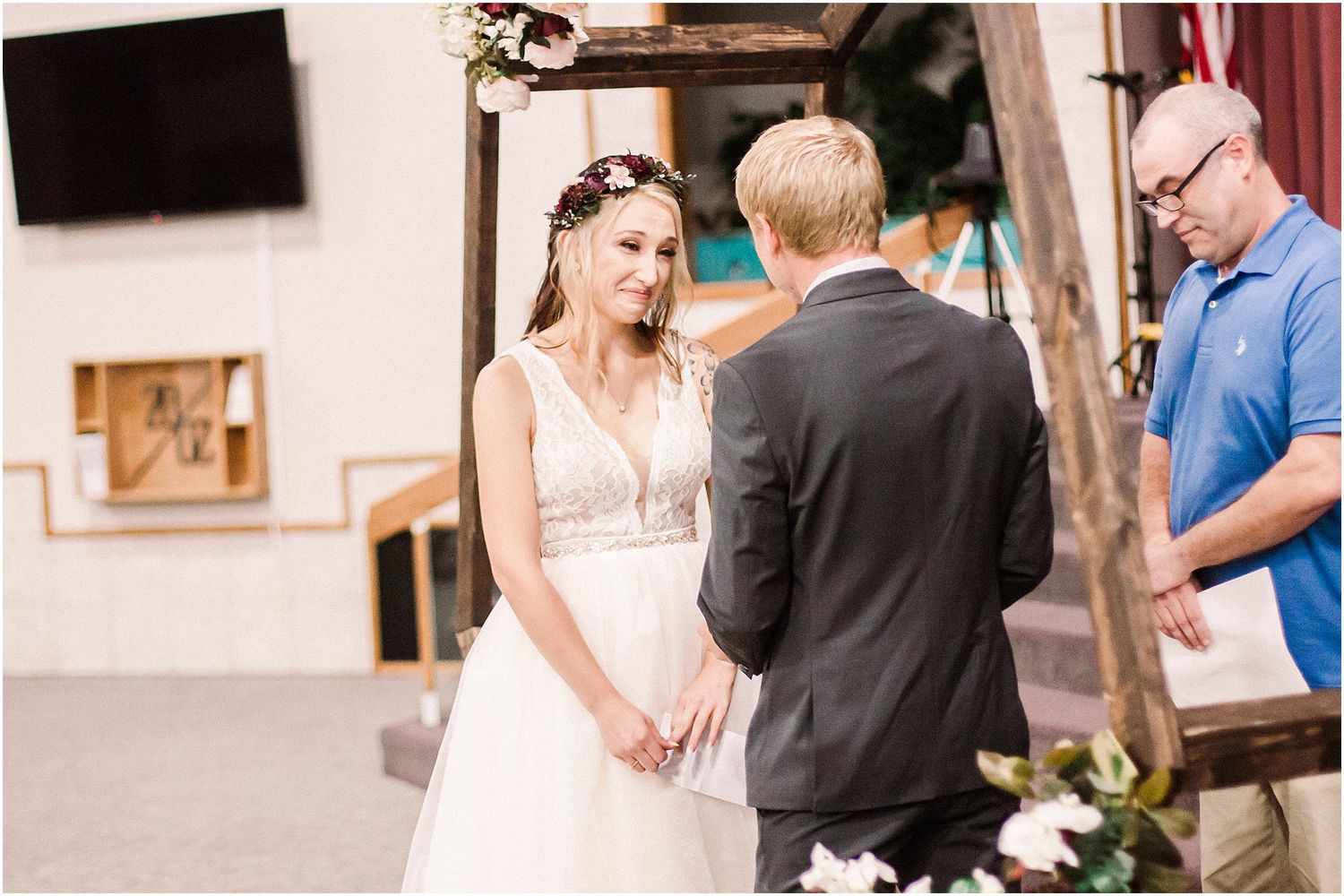 A couple shares a heartfelt moment during their wedding ceremony under a rustic wood arch.