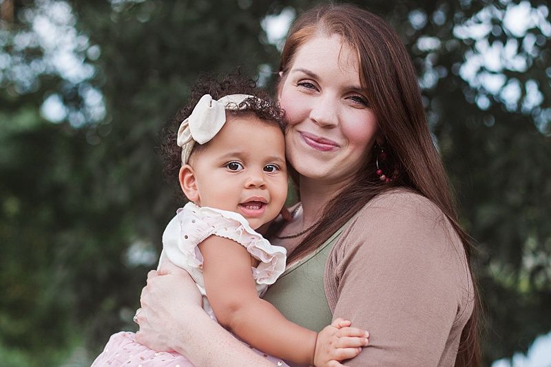 Loving outdoor portrait of parent and child wearing coordinated neutral tones.