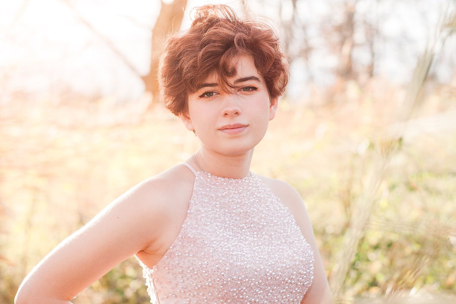 Close-up portrait in pink sequined halter dress during golden hour.