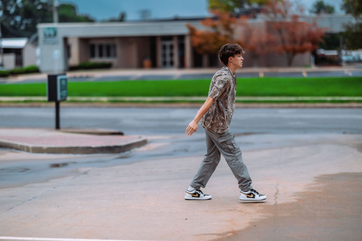 A skateboarder performs tricks at a concrete skate park on a cloudy day.